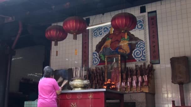 Woman places incense sticks at Kuan Im Teng — Stock Video