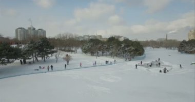 Hava kamera geriye doğru bir donmuş gölde buz pateni insanlardan uçar.