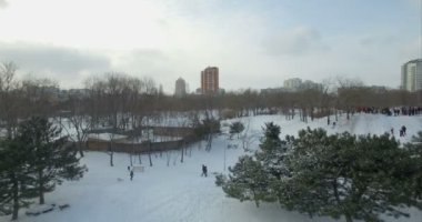 Hava kamera geriye doğru bir karla kaplı dağ kızakla çocuklardan uçar.