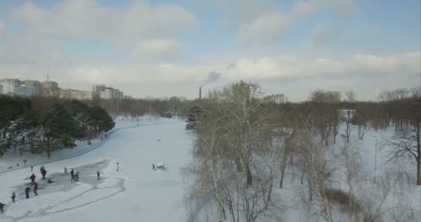空中カメラ飛ぶ後方凍った湖の上でスケートの人から — ストック動画
