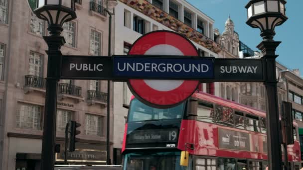 ロンドンの地下鉄の近くにショットがピカデリー サーカスで両方赤と緑 階建てバスがバック グラウンドで渡しとして署名します — ストック動画