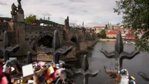 照相机幻灯片留下过去 Defocusses 栏杆和爱锁 在背景查尔斯桥梁并且布拉格城堡 — 图库视频影像