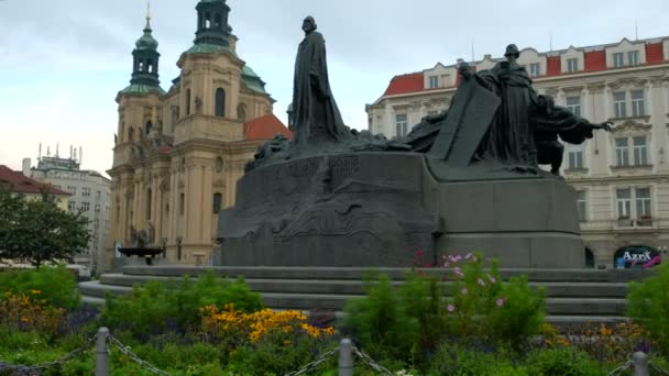 Fotoaparát snímky za květy se Jan Hus Monument a kostel svatého Mikuláše v pozadí. Praha