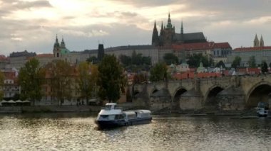 Tur tekne Prag'da Vltava Nehri üzerinde günbatımında döner. Charles Köprüsü ve Prag Kalesi'ne atış vardır