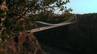 Kamera jib stil Clifton asma köprü Avon İngiltere'de ortaya çıkarmak için ağaç arkasından iner. Bahar akşam atış