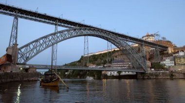 Akşam alacakaranlığında Porto 'da Ponte Luis' in altından bir sürat teknesi geçiyor. Çerçevede bir haham teknesi var.. 