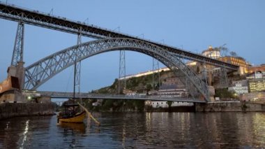 Portekiz, Porto 'da akşam alacakaranlığı sırasında Luis Köprüsü' nün düşük açılı klibi. Tahta haham teknesi ön planda.