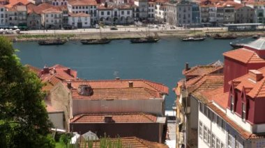 Porto 'nun kırmızı çatılarının arkasındaki Douro Nehri' ni geçen büyük bir tur teknesi. Arka planda Haham tekneleriyle ünlü Gaia gezinti güvertesi var.