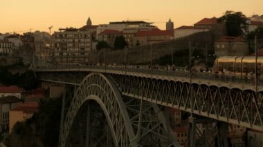 Günbatımında Porto Köprüsü 'nden geçen tramvaylar ve yayalar. Bir bahar akşamı çekildi. 