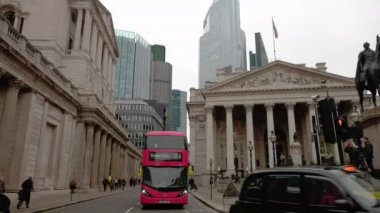 Royal Exchange ve Bank of England 'dan geçen kırmızı Londra otobüsünü takip ediyor. 22 Bishopsgate 'in tepesi bulutların ardında.