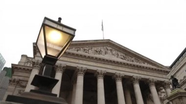 Londra şehrinde Royal Exchange 'in ön cephesinden eski lambaların arkasında kayan kamera