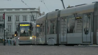 Brüksel 'deki Rue Royale' de birbirinin yanından geçen modern tramvay ve otobüslerin alçak açılı çekimi. Arka planda Bouillon ve Palais de Justice 'in Godfrey heykeli var.