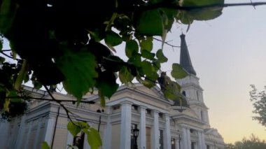 Kamera, Odessa 'daki Spaso-Preobrazhensky Katedrali' ni bir yaz akşamı gün batımında ortaya çıkarmak için yaprakların arkasından kayar.