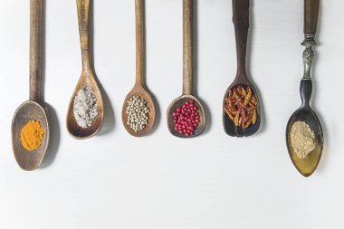 Beyaz arka planda çeşitli baharatlarla klasik kaşıklar. 