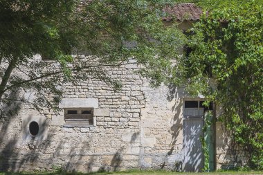 Güneşli bir günde yeşil parkta kiremit çatılı antik taş ev.