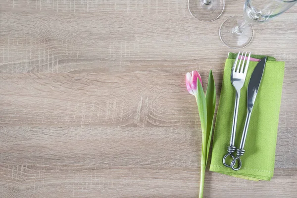 用粉红郁金香 锻造的叉子和刀在绿色餐巾上摆放餐桌 — 图库照片