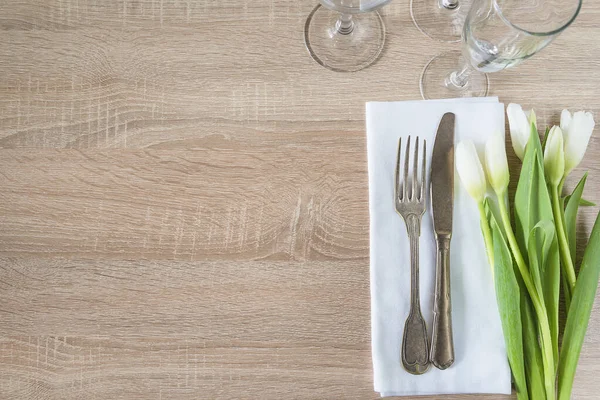 Beyaz laleler ve klasik çatal bıçaklarla dolu romantik masa ortamları.
