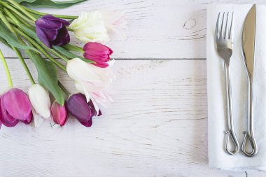 Beyaz keten peçetede klasik çatal bıçak seti ile romantik masa ayarları