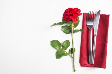Kırmızı gül ve güzel çatal bıçaklı romantik masa.