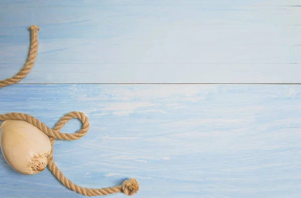 Yaz plajı konsepti. Mavi ahşap üzerinde güzel bir deniz kabuğu ve ip.
