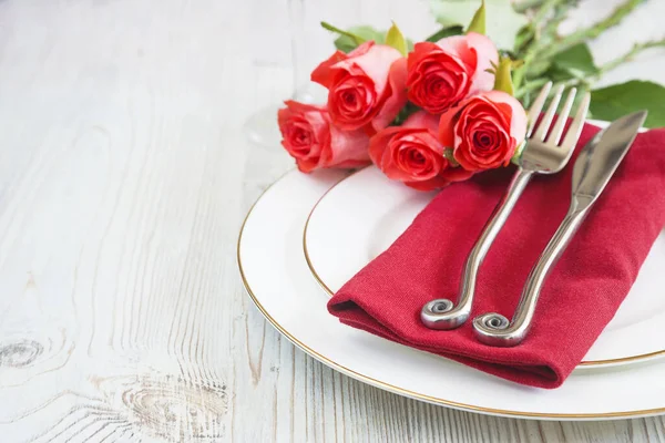 Romantic table setting. Forged fork and knife on red napkin and