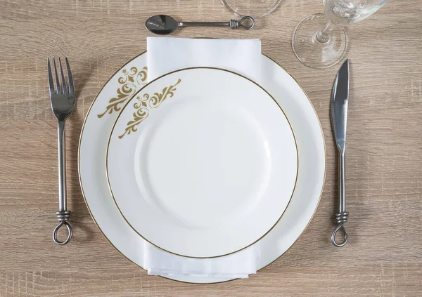 Traditional table setting. Two white plates, napkin, forged knife, fork, spoon, set of wineglasses — Stock Image Traditional Table Setting Two White Plates Napkin Forged Knife Fork Stock Picture