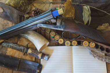 Güzel bir av tüfeği, bıçak, boynuz ve defter.