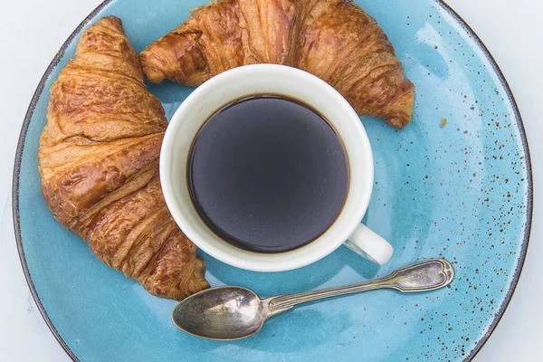 Traditional french breakfast. Cup of espresso and two hot croissants