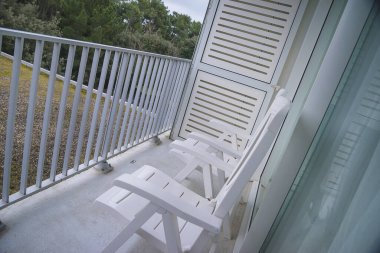 Balkonda iki beyaz iskemle.