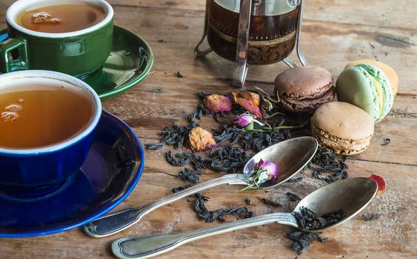 Tea time concept. Two vintage cups of tea, spoons, dry tea with rose buds