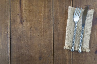 Çuval bezinde el yapımı çatal ve bıçak ve eski ahşap arka plan.