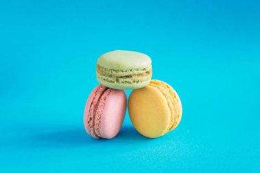 Mavi arka planda üç pembe, sarı ve yeşil Fransız kurabiyesi.