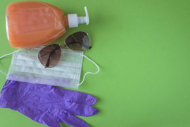 Summer Covid 19 koruması demek. Mor lastik eldivenler, tıbbi maske, güneş gözlüğü ve bir şişe sabun.