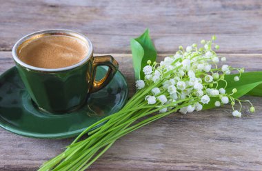 Bir fincan yeşil kahve ve vadideki zambaklar. 