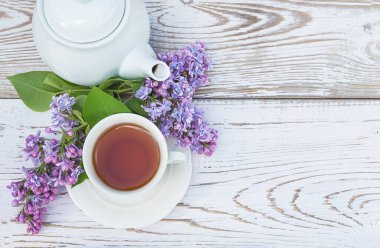 Spring Tea saat davetiyesi. Beyaz çay, çaydanlık ve bir demet leylak.