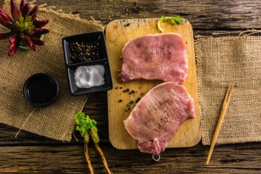 Üstten Görünüm çiğ domuz eti iki adet baharat ve biber var. Yağ ve tuz eski ahşap tablo.