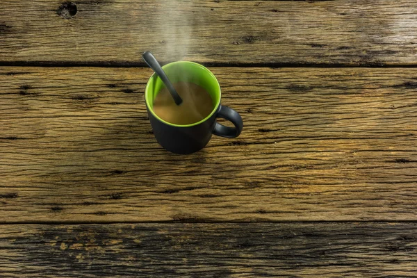 Un vaso de té caliente sobre una vieja mesa de madera . — Foto de Stock