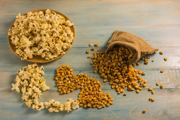 Maíz seco y palomitas de maíz en una mesa de madera . — Foto de Stock