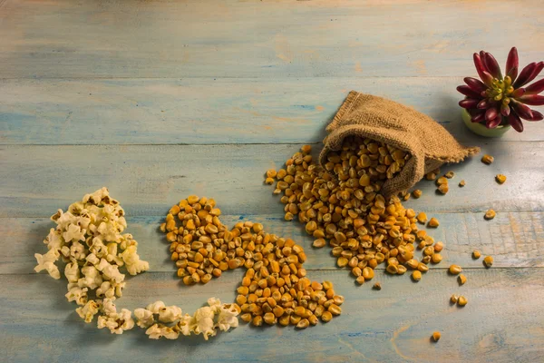 Maíz seco y palomitas de maíz en una mesa de madera . — Foto de Stock