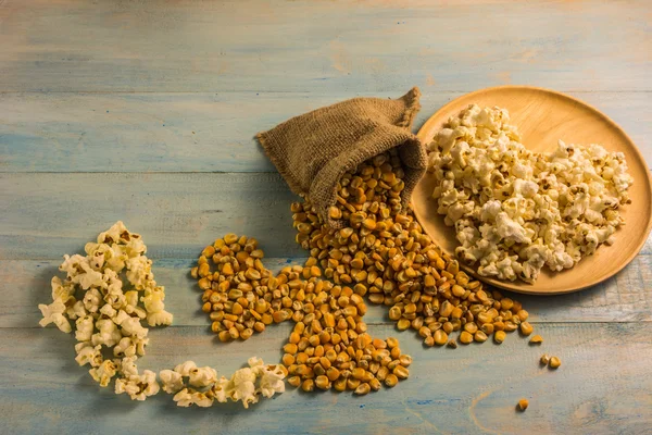 Maíz seco y palomitas de maíz en una mesa de madera . — Foto de Stock