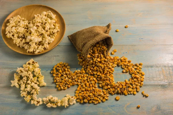 Maíz seco y palomitas de maíz en una mesa de madera . — Foto de Stock