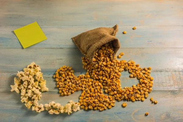 Maíz seco y palomitas de maíz en una mesa de madera . — Foto de Stock