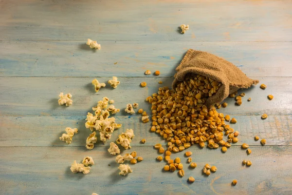 Maíz seco y palomitas de maíz en una mesa de madera . — Foto de Stock