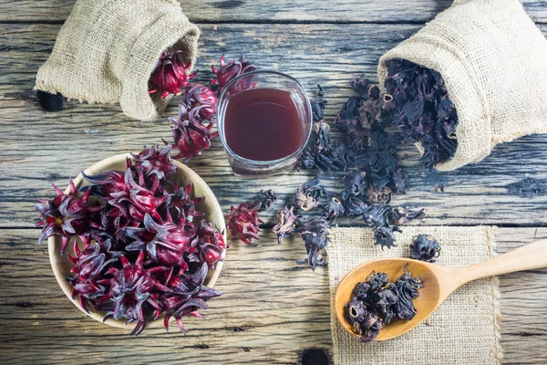 Taze roselle, kurutulmuş roselle ve ahşap bir masa roselle suyu.