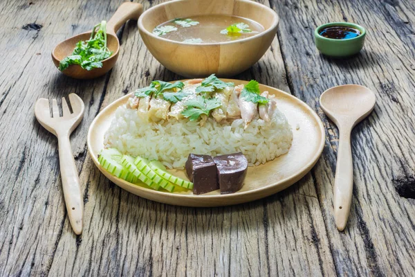 Hainanese tavuklu pilav bir tabakta çorba ve ahşap bir masa sosu ile birlikte. 