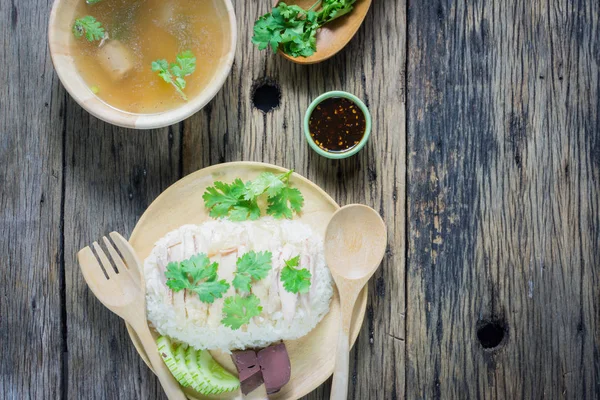 Vista superior, arroz de pollo Hainanese en un plato junto con la sopa y la salsa en una mesa de madera . — Foto de Stock