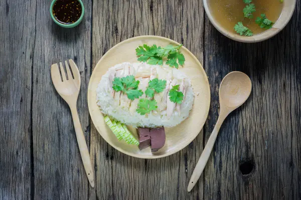 Vista superior, arroz de pollo Hainanese en un plato junto con la sopa y la salsa en una mesa de madera . — Foto de Stock