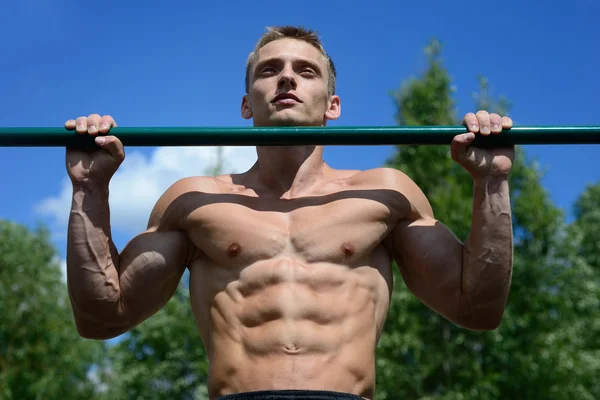 Hombre musculoso practicar entrenamiento callejero en un gimnasio al aire libre —  Fotos de Stock