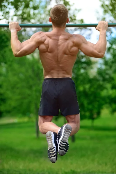 Hombre musculoso practicar entrenamiento callejero en un gimnasio al aire libre — Foto de Stock