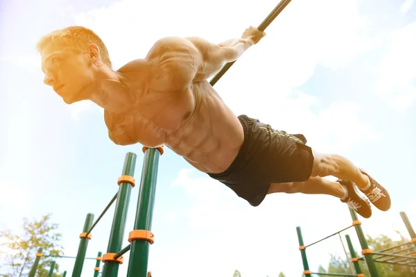 Muskulöse Mann üben Straße Workout in einem Outdoor-Fitnessstudio — Stockfoto